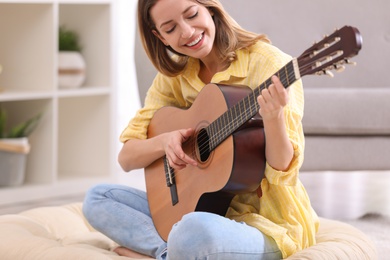 Young woman playing acoustic guitar at home