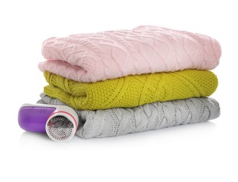 Photo of Modern fabric shaver and woolen clothes on white background