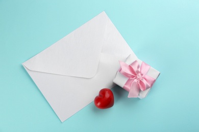 Beautiful gift box, envelope and red heart on turquoise background, flat lay. Valentine's day celebration