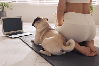 Woman with dog watching online yoga class at home, closeup