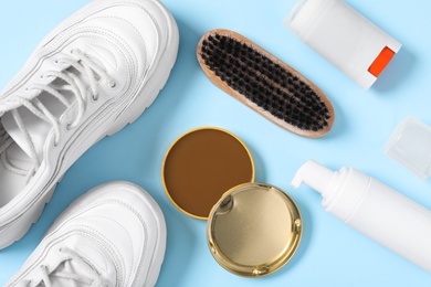 Flat lay composition with stylish footwear and shoe care accessories on light blue background