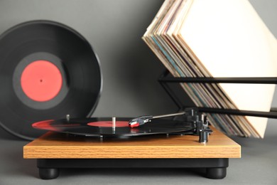 Modern player and vinyl records on grey background