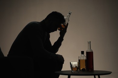 Silhouette of addicted man with alcoholic drink indoors