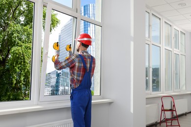 Worker using suction lifters during plastic window installation indoors
