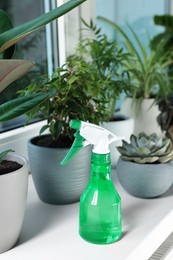 Photo of Different beautiful houseplants and spray bottle with water on window sill indoors