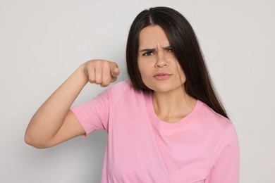 Aggressive young woman pointing on light grey background