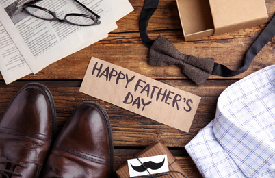Flat lay composition with words HAPPY FATHER'S DAY and male accessories on wooden table