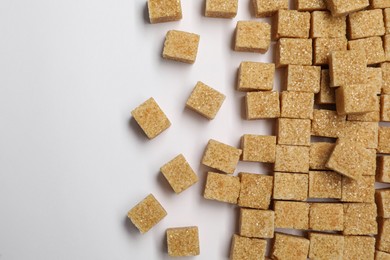 Brown sugar cubes on white background, flat lay. Space for text