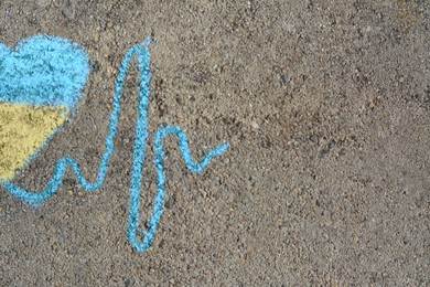 Cardiogram line with heart drawn by blue and yellow chalk on asphalt, top view. Space for text