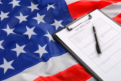 Photo of Visa application form and pen on American flag. Immigration to USA