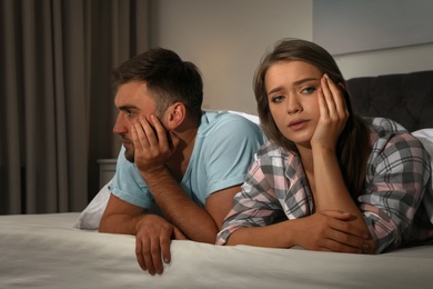 Photo of Young couple with relationship problems in bed at nighttime