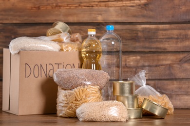 Photo of Donation box with food on wooden background