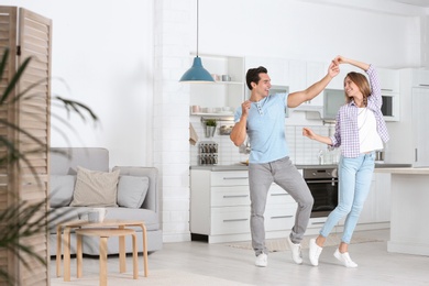 Beautiful young couple dancing in kitchen at home