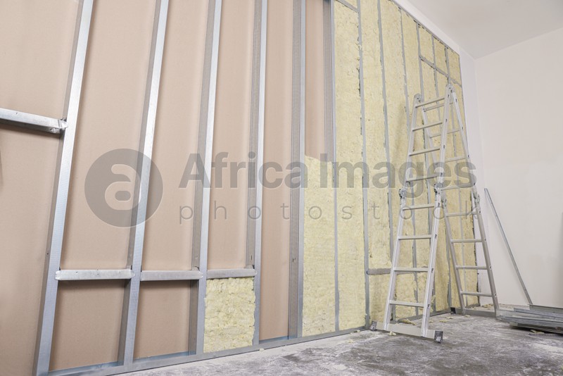Photo of Ladder near wall with metal studs and insulation material indoors