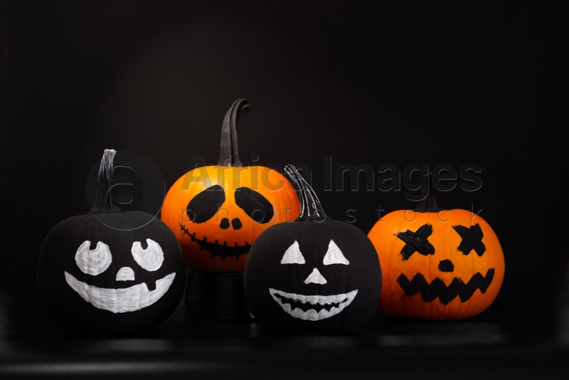Photo of Halloween celebration. Pumpkins with drawn faces on table in darkness