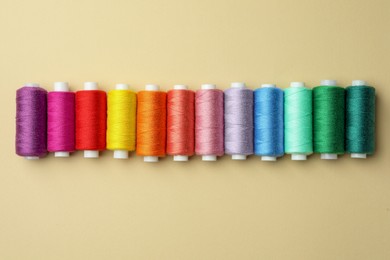 Set of colorful sewing threads on beige background, flat lay