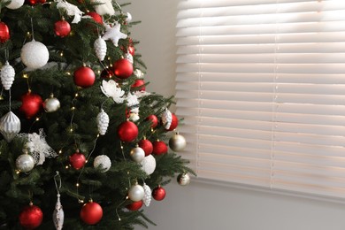 Beautifully decorated Christmas tree near window indoors. Space for text