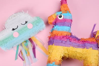 Photo of Different bright pinatas on pink background, flat lay