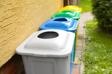 Photo of Many colorful recycling bins near yellow wall outdoors