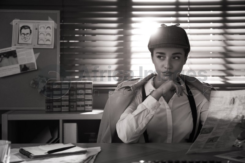 Old fashioned detective with newspaper at table in office. Black and white effect
