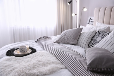 Bed with cushions and striped blanket in room. Interior design