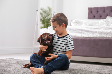 Little boy with puppy on floor in bedroom. Friendly dog