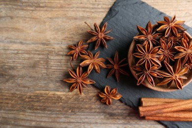 Photo of Aromatic cinnamon sticks and anise stars on wooden table, flat lay. Space for text