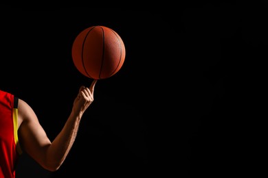Basketball player spinning ball on black background, closeup. Space for text