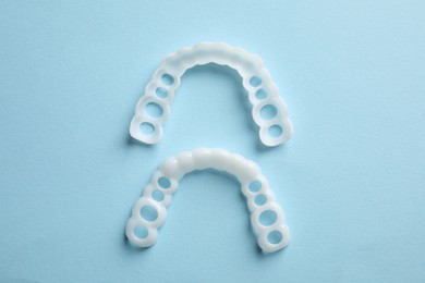 Photo of Dental mouth guards on light blue background, flat lay. Bite correction