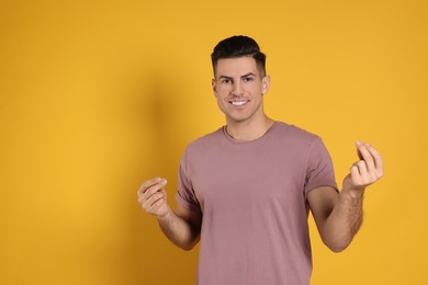 Handsome man snapping fingers on yellow background. Space for text