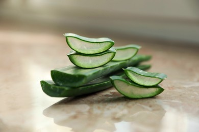 Green aloe vera leaves and slices on marble table, closeup