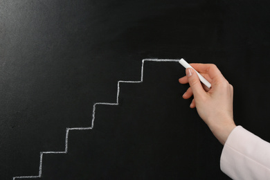 Photo of Woman drawing stairs on chalkboard, closeup. Career promotion concept