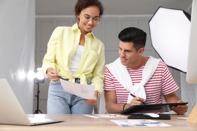 Professional retoucher with colleague working at desk in photo studio