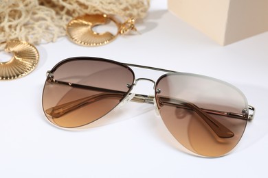 New stylish elegant sunglasses and jewelry on white background, closeup