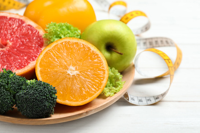 Fruits, vegetables and measuring tape on white wooden background, closeup. Visiting nutritionist