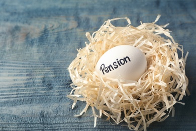Egg with word PENSION in nest on wooden background. Space for text