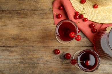 Delicious cherry wine with ripe juicy berries on wooden table, flat lay. Space for text