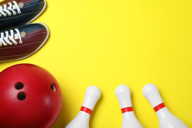 Bowling ball, shoes and pins on yellow background, flat lay. Space for text