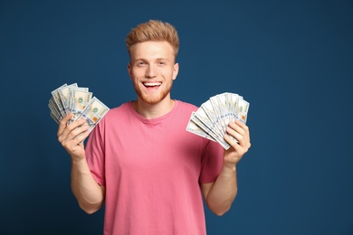 Portrait of happy lottery winner with money on blue background
