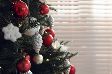 Beautifully decorated Christmas tree near window indoors, closeup. Space for text