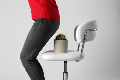 Woman sitting down on chair with cactus against white background, closeup. Hemorrhoids concept