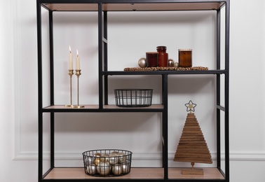 Stylish shelving unit with Christmas decor near white wall indoors. Interior design