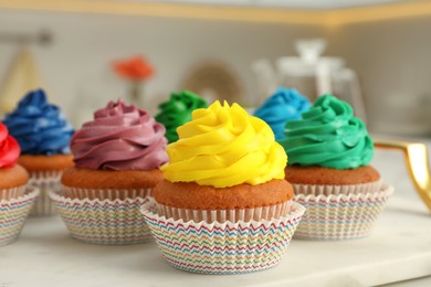 Delicious cupcakes with colorful cream on white board, closeup