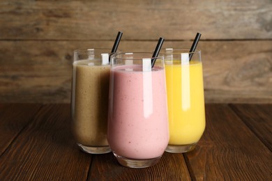 Photo of Glasses with different smoothies on wooden table