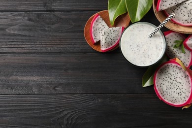 Delicious pitahaya smoothie and fresh fruits on black wooden table, flat lay. Space for text
