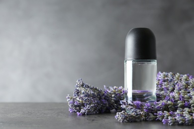 Deodorant and lavender flowers on grey stone table. Space for text