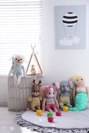 Photo of Funny stuffed toys on floor near window. Decor for children's room interior