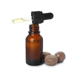 Bottle of nutmeg oil, pipette and nuts on white background