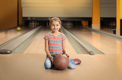 Little girl with ball in bowling club