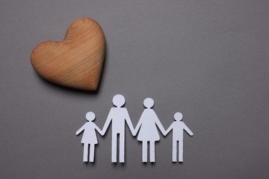 Photo of Paper family figures and wooden heart on grey background, flat lay. Insurance concept